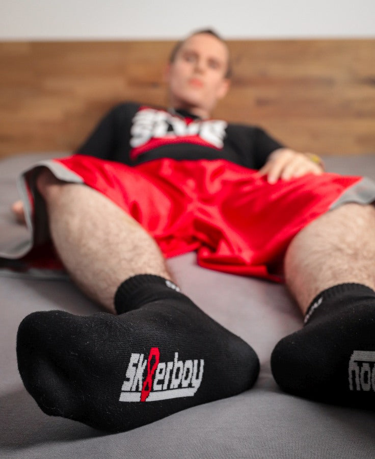 junger gay traegt schwarze quarter socks von sk8erboy mit logo am bund und auf der unterseite in nahaufnahme