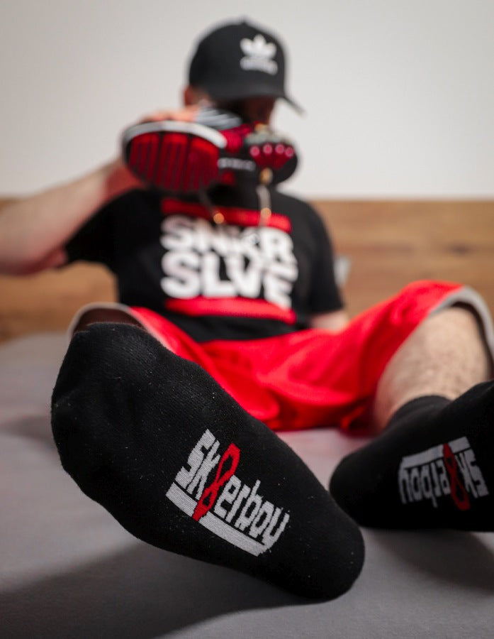 junger gay traegt schwarze quarter socks von sk8erboy mit logo am bund und auf der unterseite in nahaufnahme