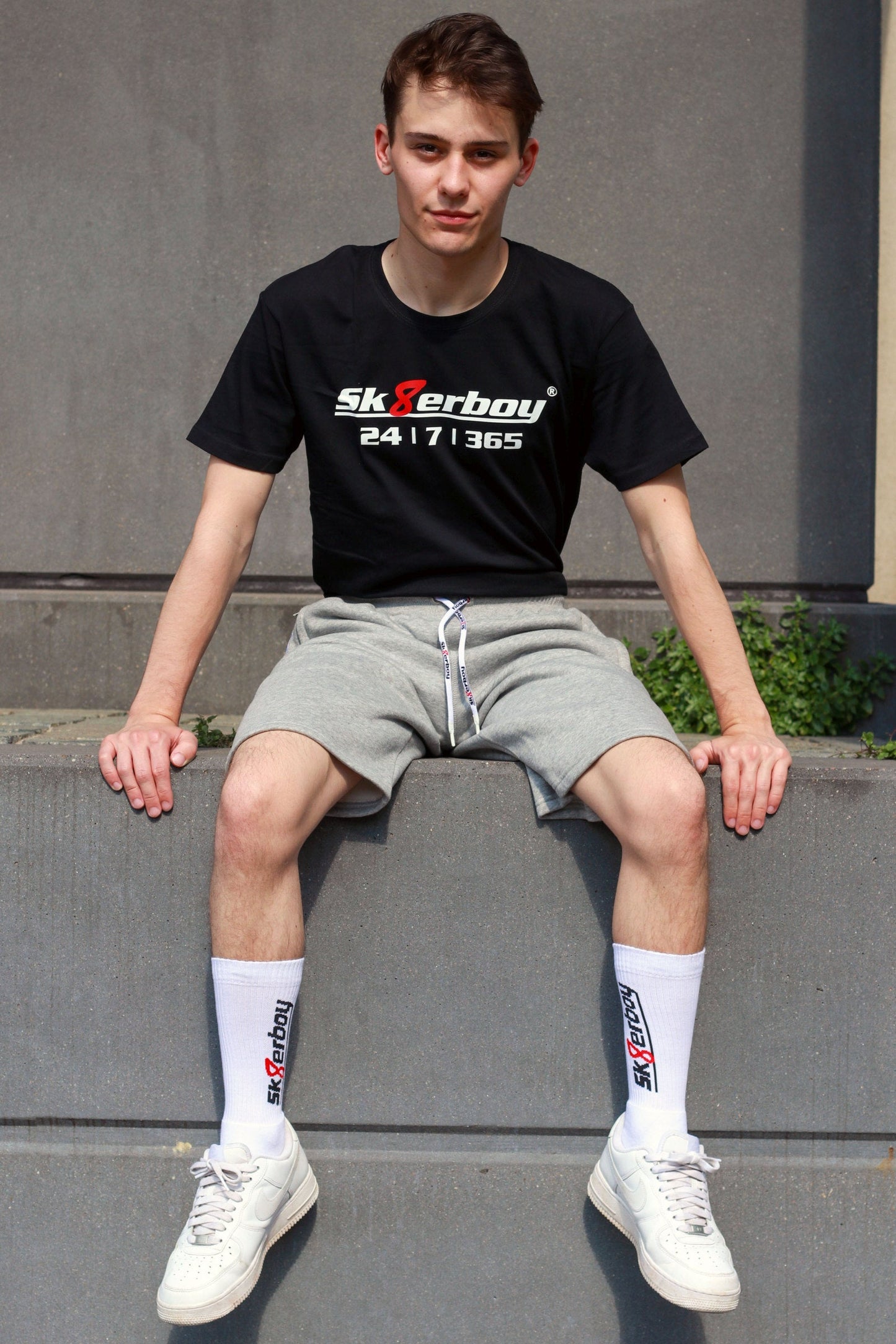 junger typ trägt grauen sk8erboy trainingsanzug in lang mit passender hose und 365 t-shirt zu seinen weißen nike sneaks und crew socks