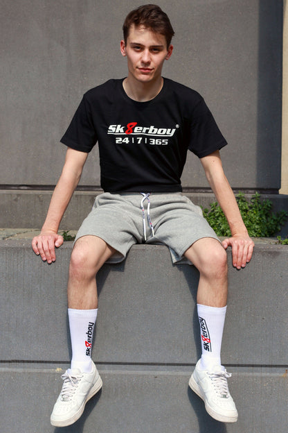 junger typ trägt grauen sk8erboy trainingsanzug in lang mit passender hose und 365 t-shirt zu seinen weißen nike sneaks und crew socks