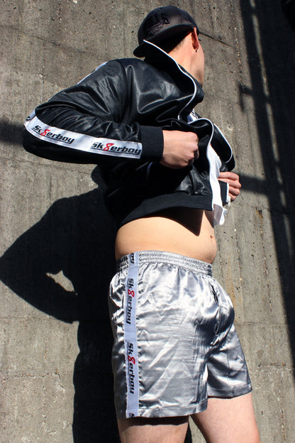 sk8erboy shiny glaenzend satin silver silber glanz boxershort brief mit fettem sk8erboy streifen in weiss mit schwarzem Schriftzug und roter acht 8 seine sexy behaarten beine enden in geilen nike Shox nz sneaker sneax von nike weiss Leder perfekt zu lecken die deluxe socks in weiss von sk8erboy mit schwarzen ringen runden das perfekt ab das logo ist gestickt mit einer roten acht der boy Bengel Kerl mann steht vor einer Backsteinwand an einem roten lostplace Fabrik weg beton Jacke wird hochgezogen