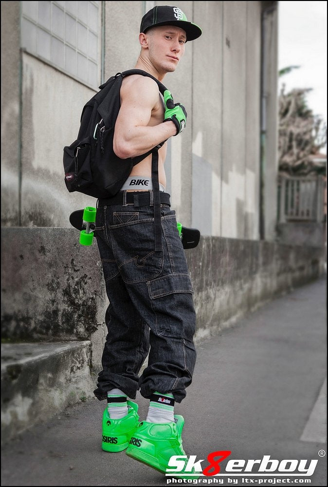 skater boy mit baggy in der stadt und rucksack trägt grüne sneaker mit passenden sk8erboy deluxe socks in neon-gruen