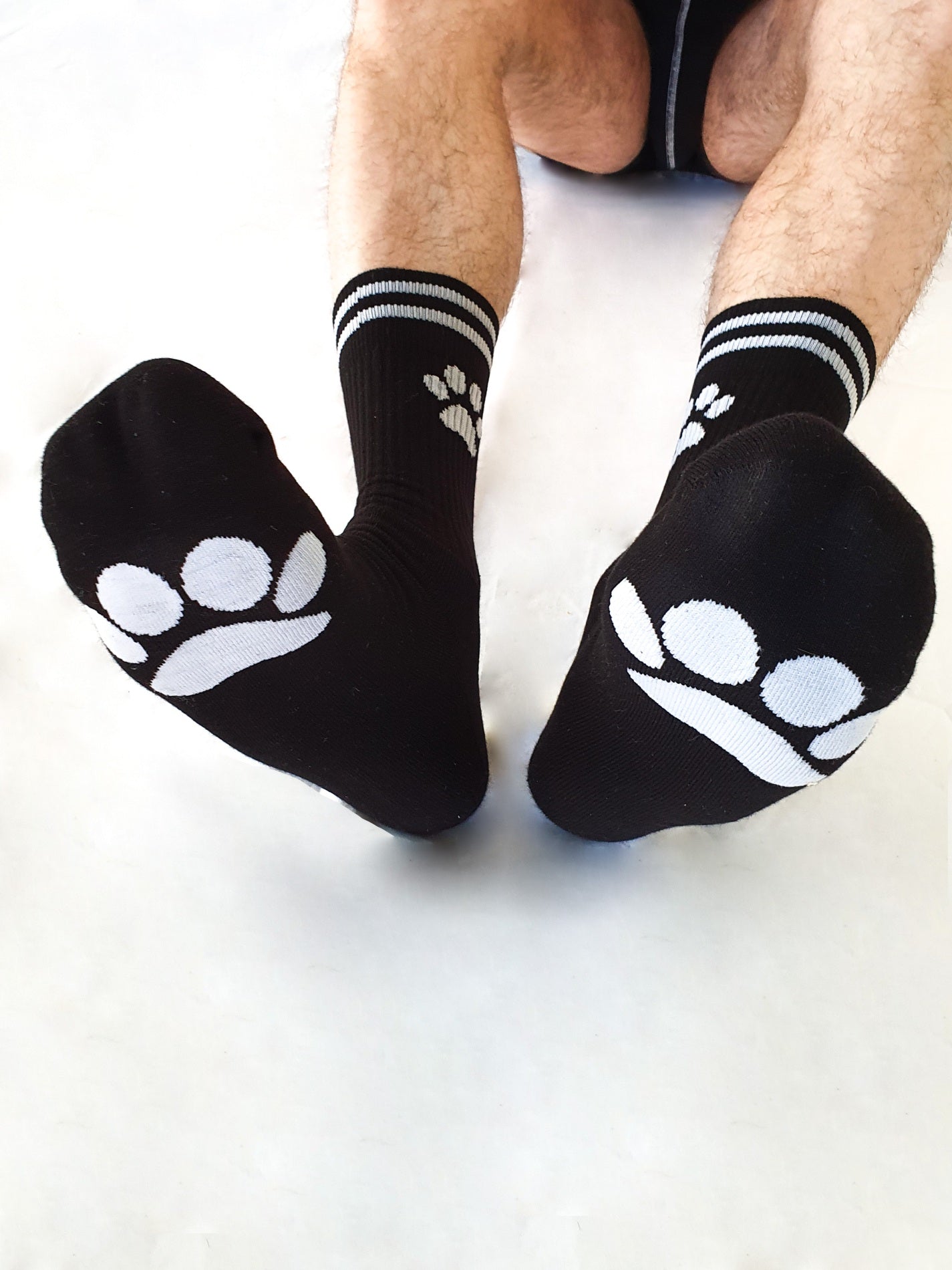 sk8erboy puppy socken schwarz von vorne unten mit sichtbaren hundepfoten auf der unterseite und an der beinseite in weiss für doggy und puppyplay