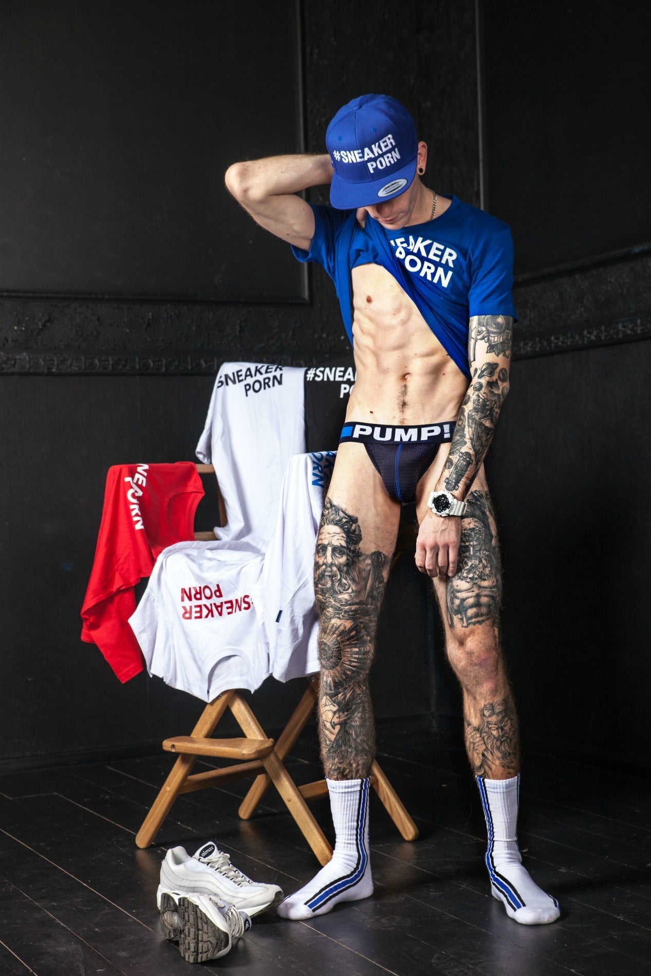 scharfer junge mit jock von pump! zeigt seine tattoos und trägt ein blaues t-shirt und kappe mit sneakerporn aufdruck und den passenden socken in weiss und royalblau mit #sneakerporn von sk8erboy