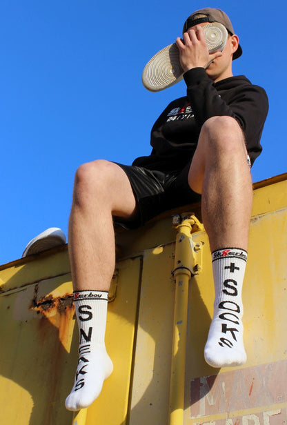 junger gay mit sneaks and socks socken von sk8erboy in weiß traegt einen schwarzen kaputzenpullover mi 365 7 24 aufdruck auf einem kontainer sitzend snifft an seinen nike air turnschuhen