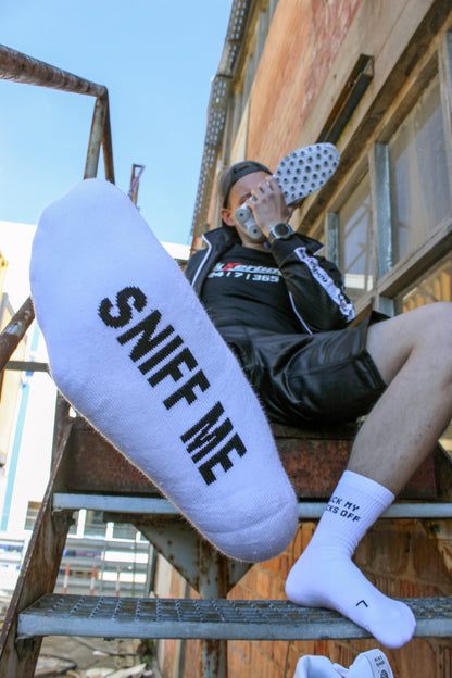 sk8erboy sniff me socks socken mit einem fetten Aufschrift in schwarz auf den weissen socken der boy snifft hart an seinen nike Shox weiss aus Leder er traegt dabei eine sk8erboy shiny short kurze hose in schwarz glaenzend und eine sk8erboy shiny glaenzende schwarze Jacke mit sk8erboy einstick auf der brust das tshirt hat den Schriftzug 24 7 365 in schwarzer Baumwolle mit weissem Schriftzug und der roten acht 8