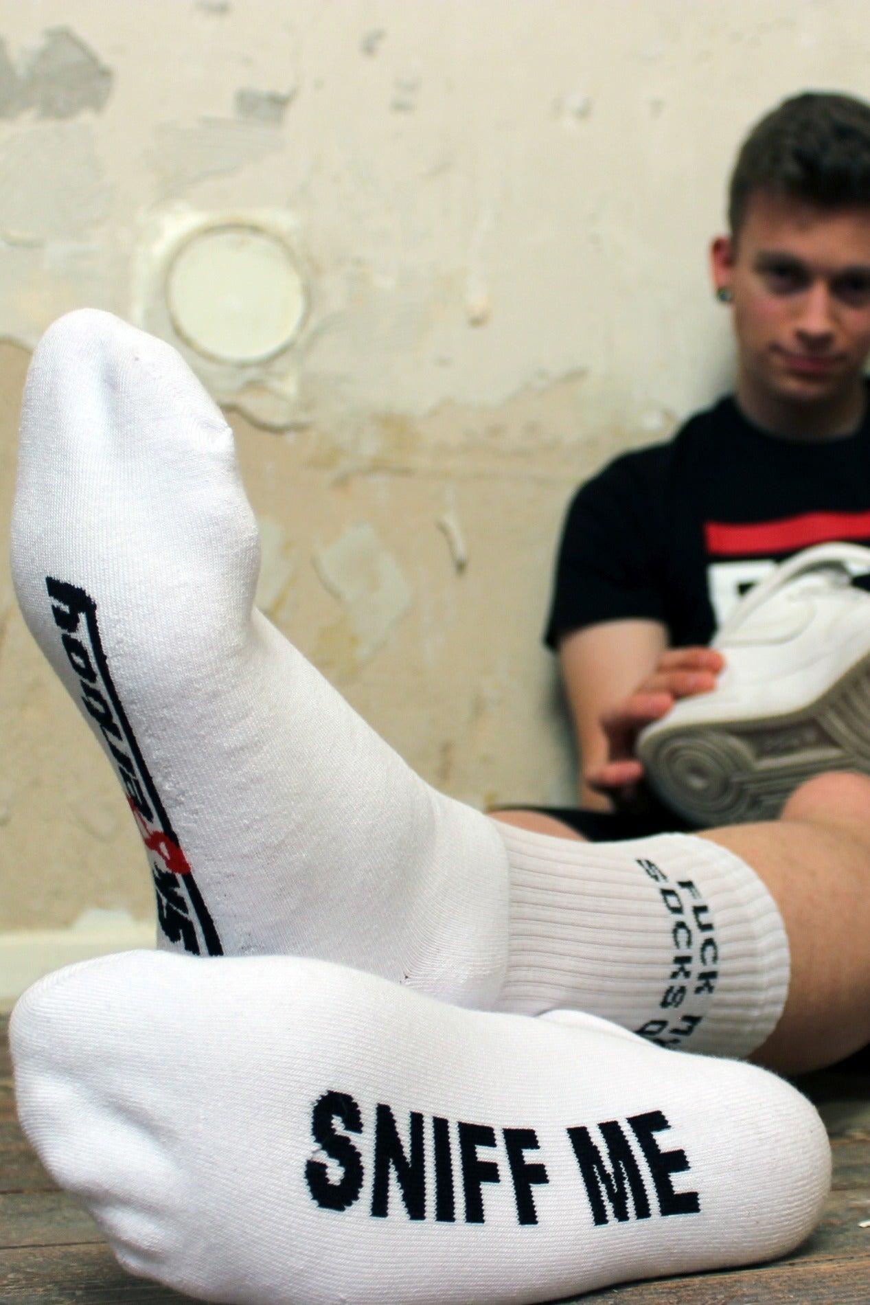 sk8erboy sniff me socks socken mit einem fetten Aufschrift in schwarz auf den weissen socken traegt ein fck abl t-shirt von sk8erboy sitzt am boden